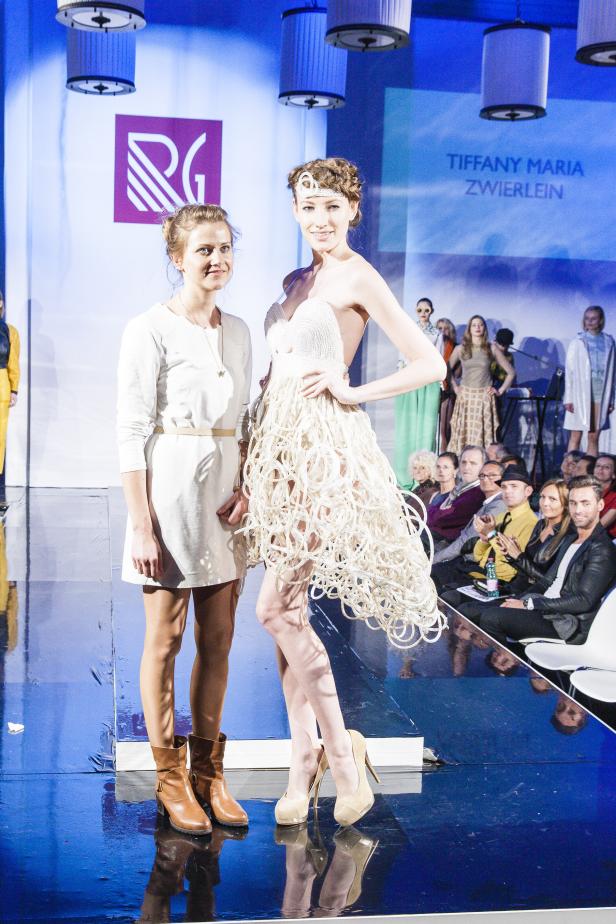 Zwei Frauen präsentieren Mode auf einer Bühne während einer Modenschau.