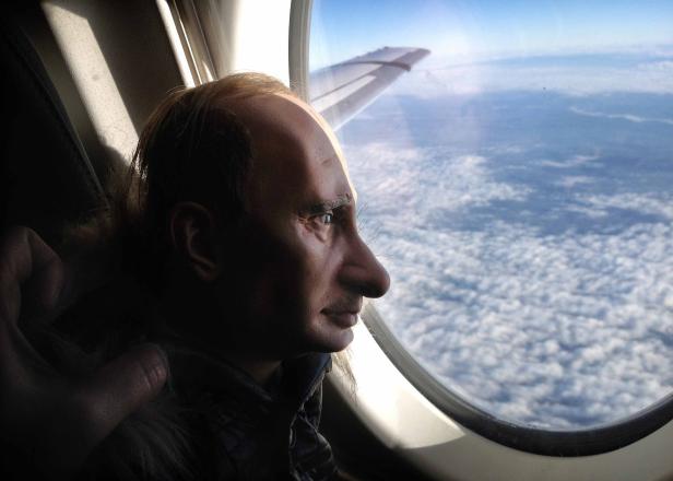 Eine Person blickt aus einem Flugzeugfenster auf die Wolken.