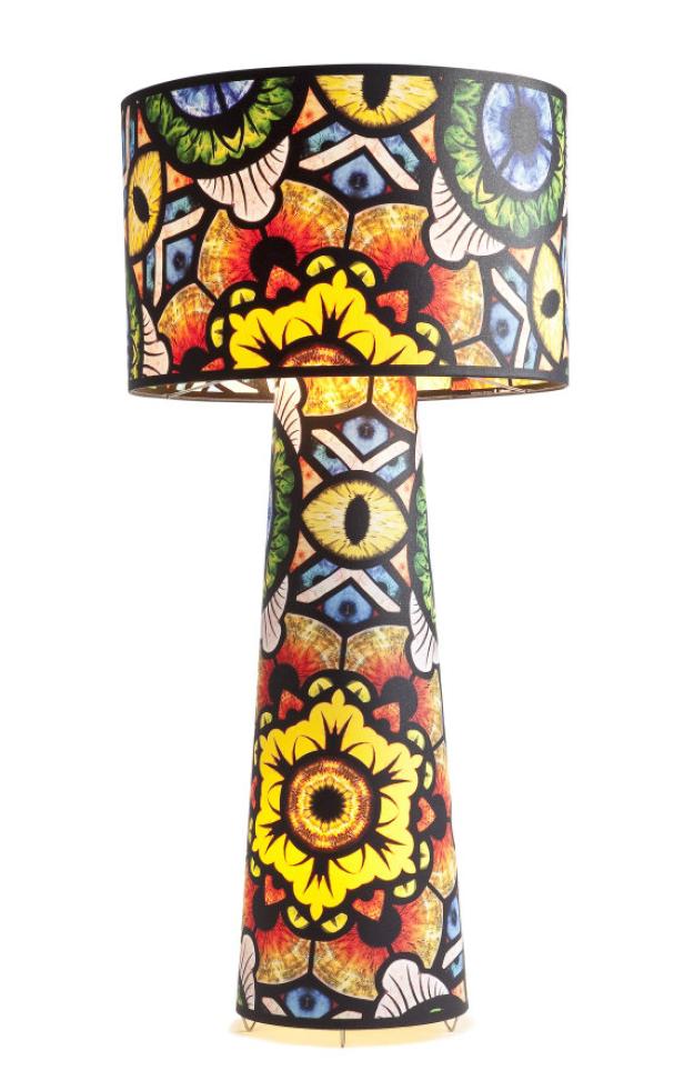 Eine Stehlampe mit einem bunten, gemusterten Lampenschirm und Fuß steht vor einem weißen Hintergrund.