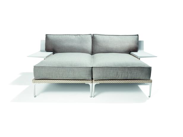 Ein graues Sofa mit weißen Beistelltischen vor einem weißen Hintergrund.