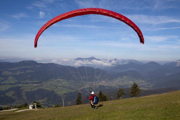 Ein Paraglider bereitet sich auf den Start vor einer Bergkulisse vor.