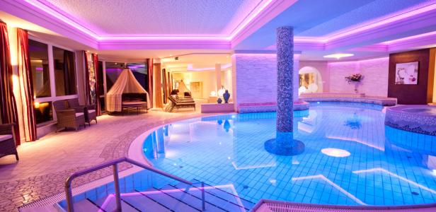 Ein Innenpoolbereich mit Liegen und Entspannungsmöglichkeiten in einem Wellnesshotel.