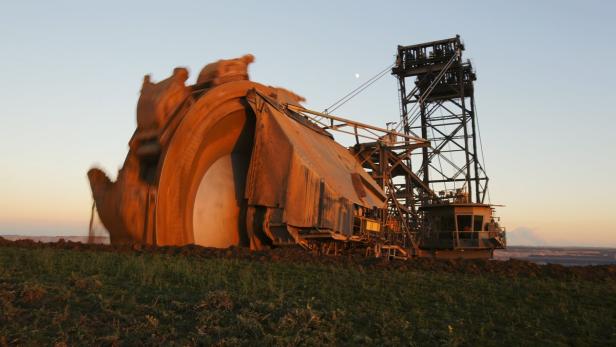 Ein riesiger Schaufelradbagger steht auf einem Feld im Abendlicht.