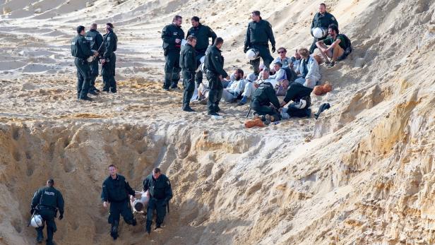 Polizisten befreien Personen aus einem Sandloch.