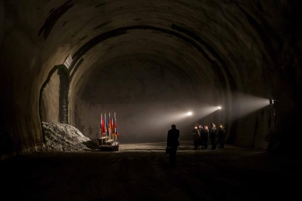 Eine Gruppe von Personen steht in einem dunklen Tunnel mit mehreren Flaggen.