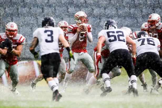 Ein Quarterback bereitet sich darauf vor, den Ball bei einem American-Football-Spiel im Regen zu werfen.