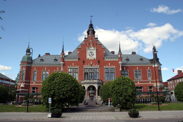 Das Rathaus von Söderköping, Schweden, mit einer Uhr und einem Denkmal im Vordergrund.