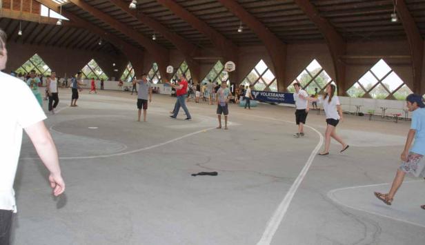 In einer Halle spielen mehrere Personen Volleyball und Basketball.