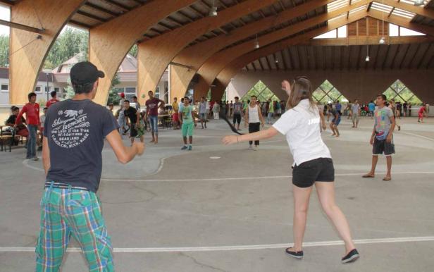 Eine Gruppe junger Leute spielt Frisbee in einer Halle.