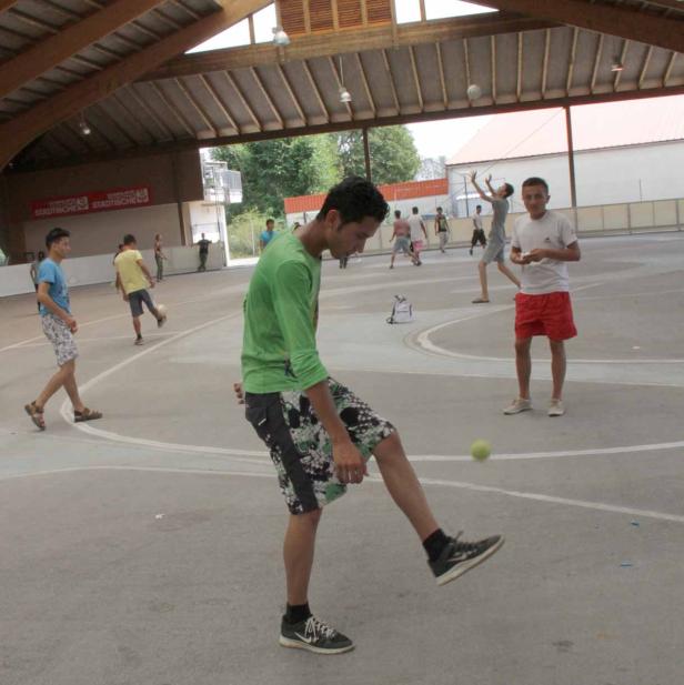 Eine Gruppe junger Männer spielt auf einem Sportplatz mit Bällen.