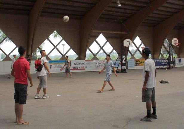 Eine Gruppe junger Männer spielt mit einem Ball in einer Halle.