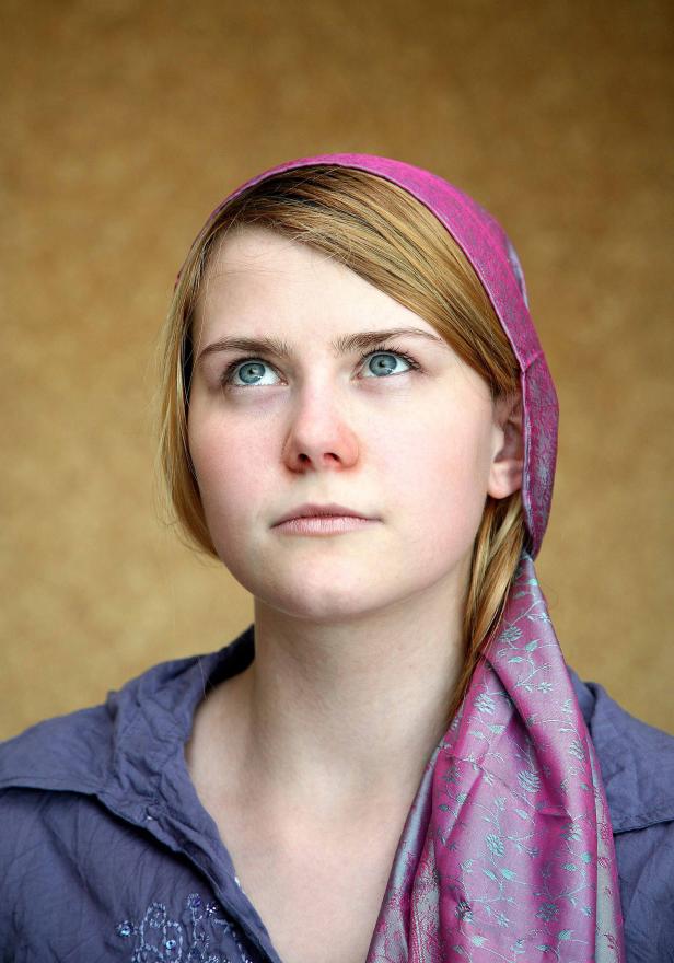 Eine junge Frau mit Kopftuch blickt nach oben.