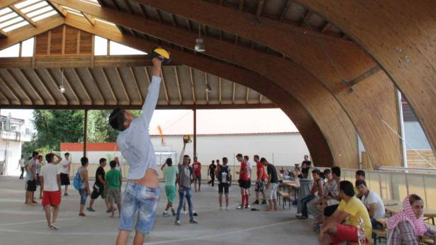Eine Gruppe junger Leute versammelt sich in einer Halle mit Holzbalken.