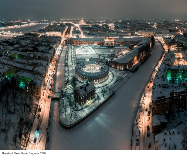 Nachtsicht auf eine verschneite Stadt mit beleuchteten Gebäuden und einem gefrorenen Fluss.