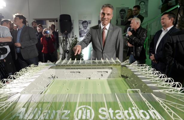Ein Mann präsentiert ein Modell des Allianz Stadions vor Publikum.