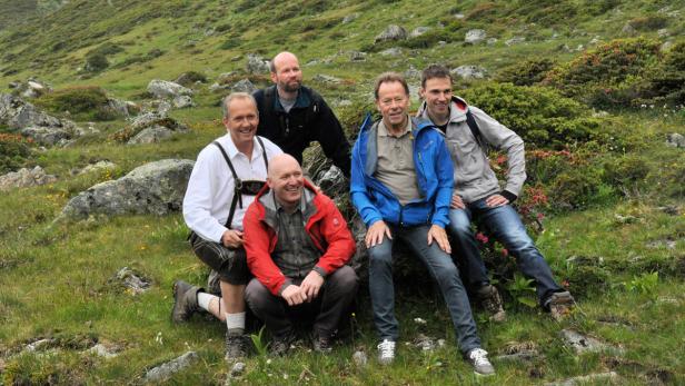 Fünf Männer posieren in einer Berglandschaft für ein Foto.