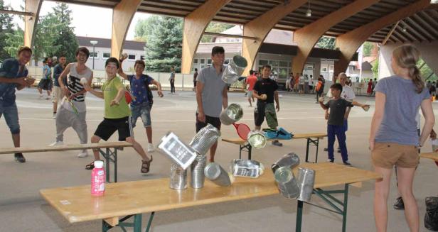 Eine Gruppe Kinder spielt Dosenwerfen im Freien.