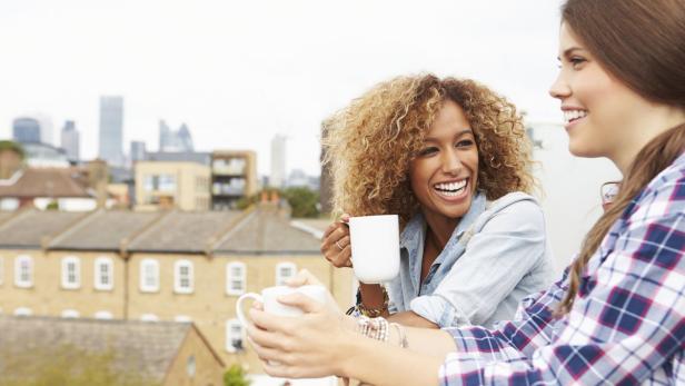 Two Women Relaxing On Rooftop Garden Drinking Coff Coca-Cola will "Coffee to go" verkaufen