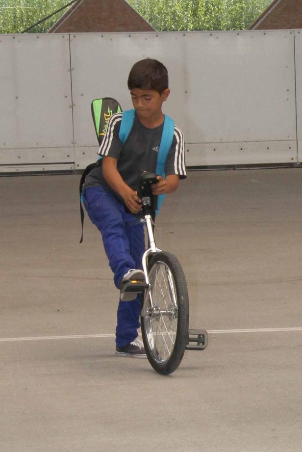 Ein Junge mit Rucksack fährt auf einem Einrad.