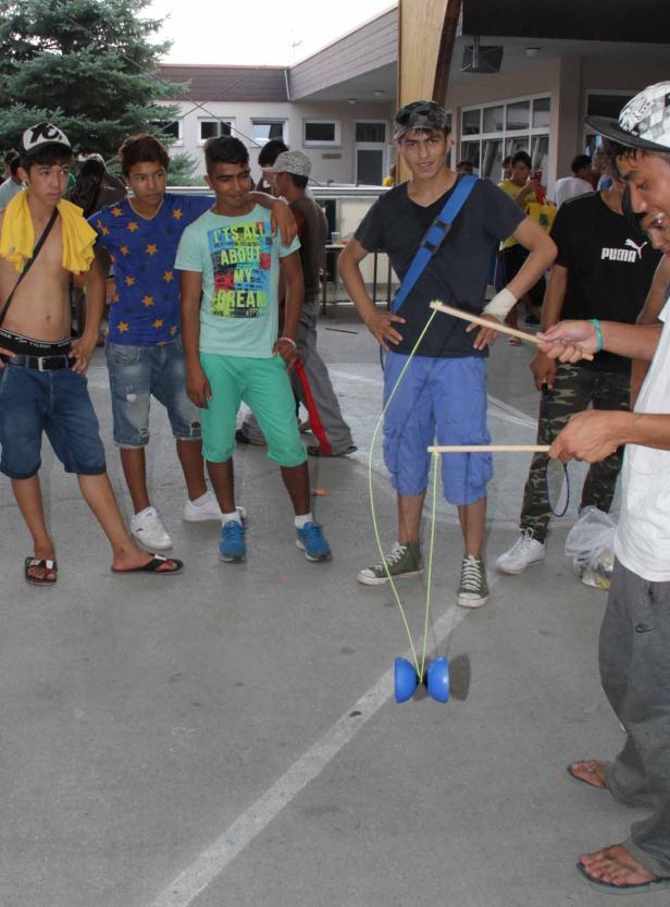 Eine Gruppe junger Männer beobachtet jemanden, der mit einem Diabolo spielt.