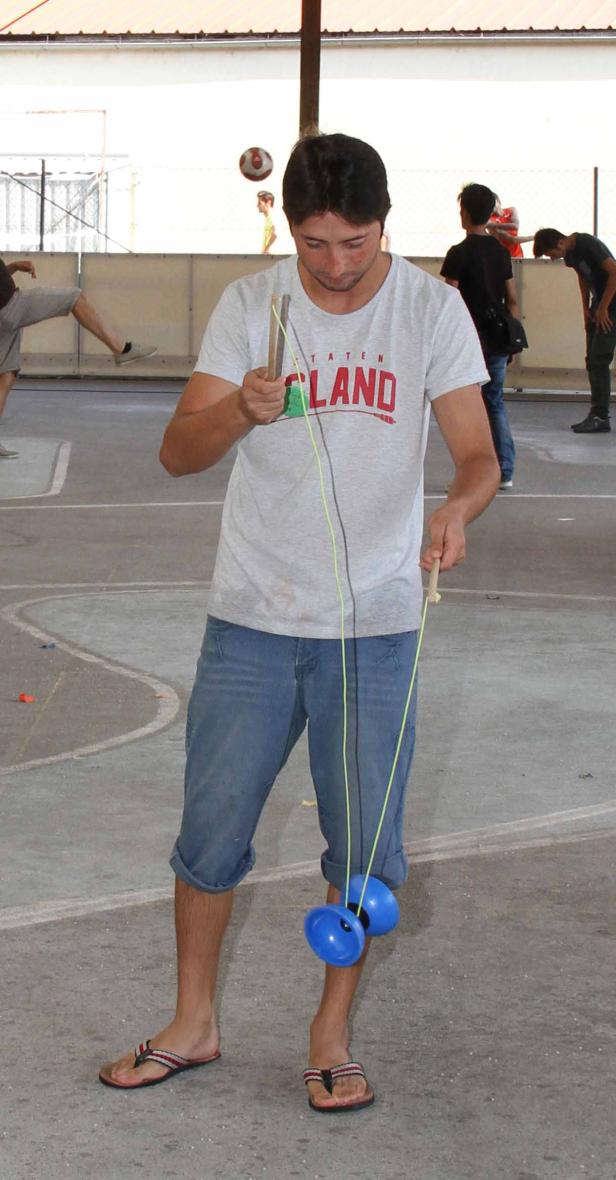 Ein Mann spielt mit einem Diabolo auf einem gepflasterten Platz.