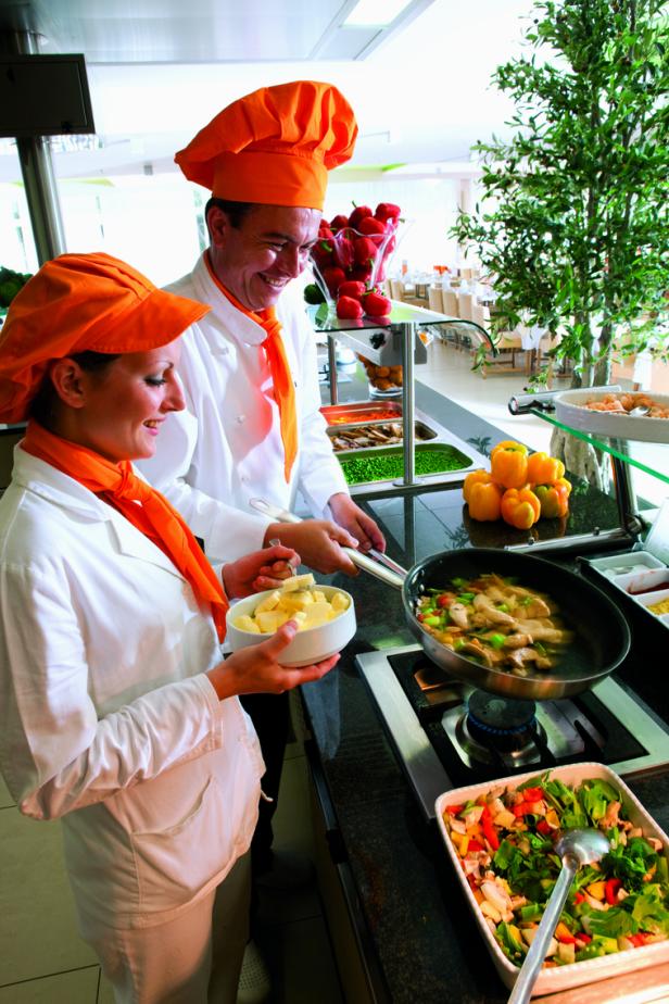 Zwei Köche bereiten in einer Hotelküche eine Mahlzeit zu.