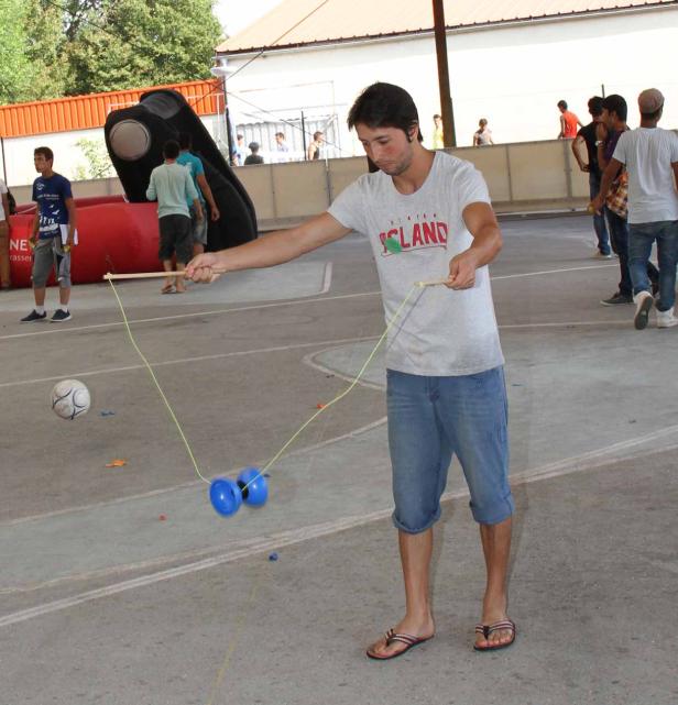 Ein Mann spielt mit einem Diabolo auf einem gepflasterten Platz.