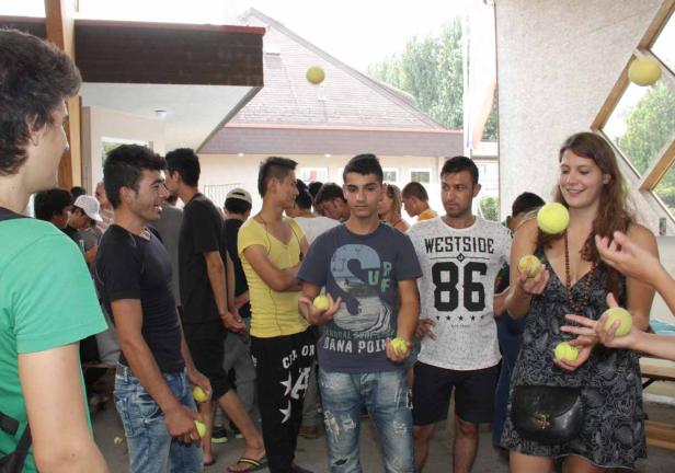 Eine Gruppe junger Leute jongliert mit Tennisbällen in einem Innenraum.