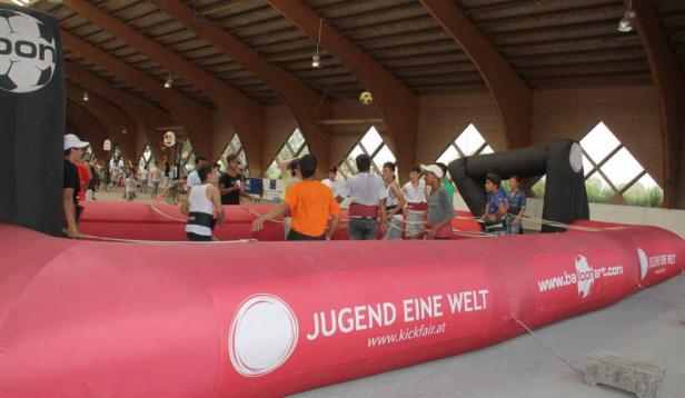 Eine Gruppe von Menschen spielt in einer aufblasbaren Arena mit einem Ball.