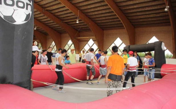 Eine Gruppe junger Leute spielt ein Spiel auf einer großen, roten, aufblasbaren Struktur in einer Halle.