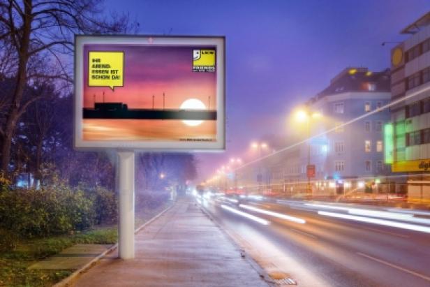 Eine Werbetafel am Straßenrand zeigt eine Sonnenuntergangsszene mit dem Text: „Ihr Abend. Essen ist schon da!“.