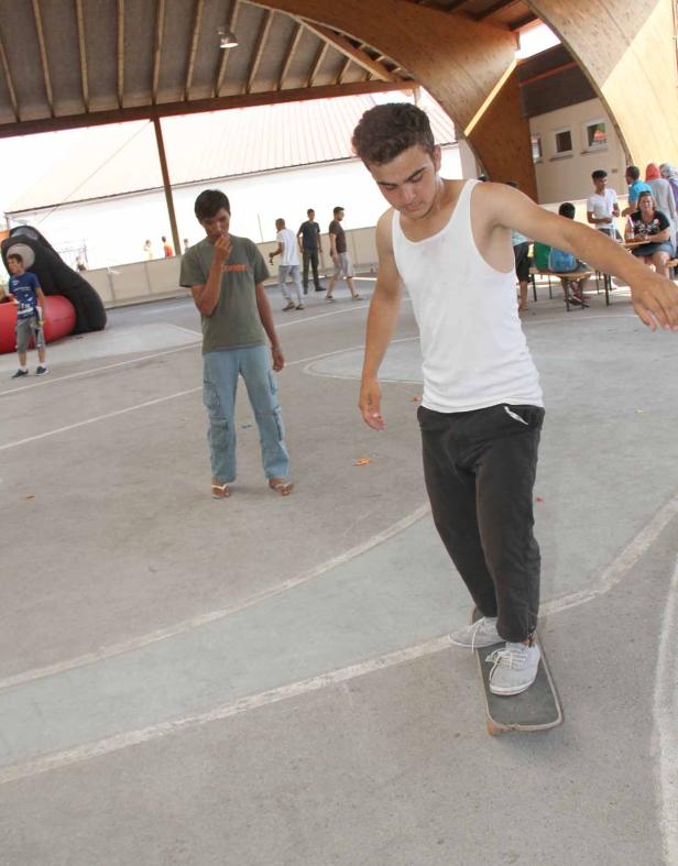 Ein junger Mann fährt auf einem Skateboard in einer Halle.