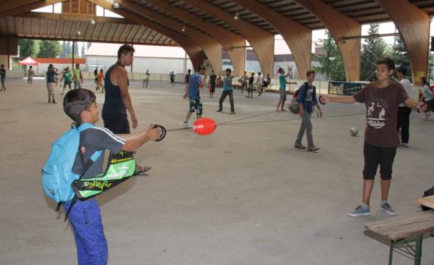 Eine Gruppe von Kindern spielt mit einem Boi-Spielzeug in einer Halle.
