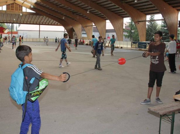 Eine Gruppe Kinder spielt mit einem Ball an einer Schnur in einer Halle.