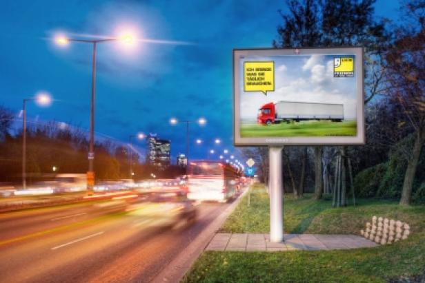 Ein Werbeplakat für LKW-Zubehör an einer Straße bei Nacht.