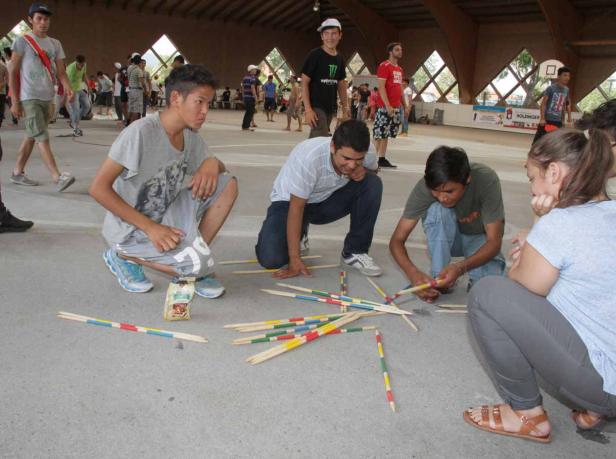 Eine Gruppe junger Leute spielt Mikado in einer Halle.