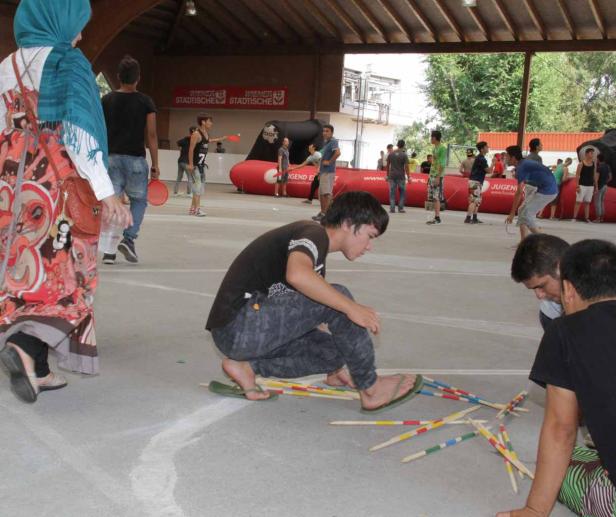 Eine Gruppe junger Leute spielt Mikado im Freien.