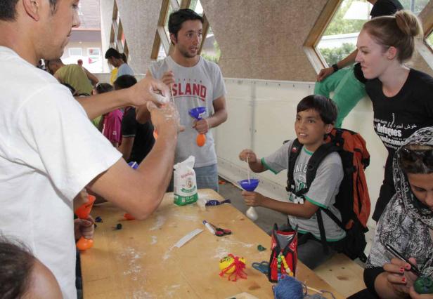 Kinder und Erwachsene basteln gemeinsam an einem Tisch.