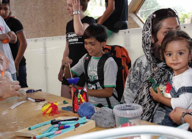 Kinder basteln an einem Tisch mit Stiften, Wolle und anderen Materialien.