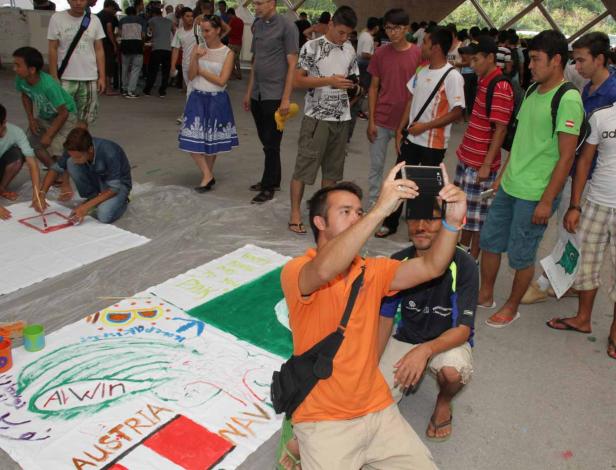 Eine Gruppe von Menschen malt Flaggen und Slogans auf große Stoffbahnen.