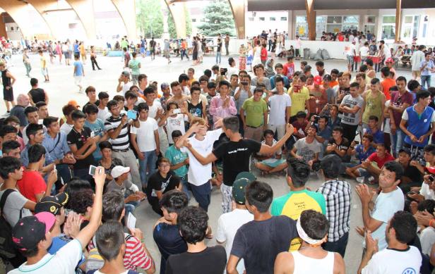Eine große Gruppe junger Menschen versammelt sich im Freien, einige filmen mit ihren Handys.