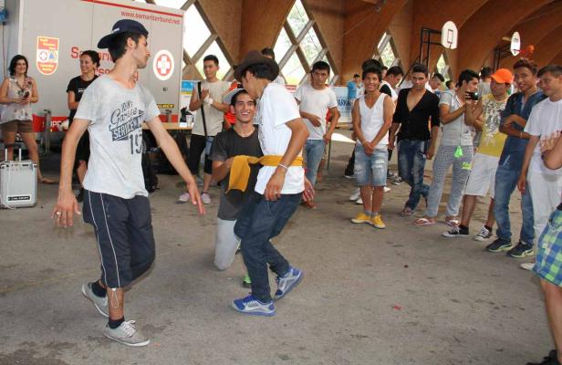 Eine Gruppe junger Männer tanzt und feiert in einer Halle.