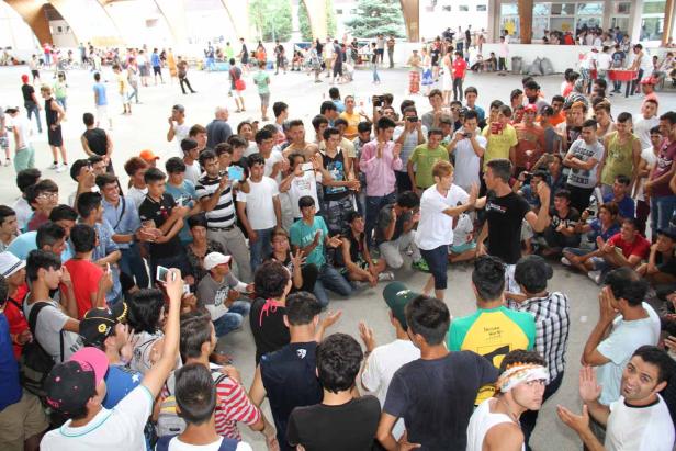 Eine große Gruppe junger Männer versammelt sich in einer Halle, einige machen Fotos.