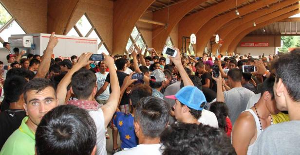 Eine große Menschenmenge drängt sich in einer Halle und filmt mit ihren Smartphones.