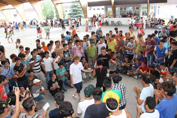 Eine Menschenmenge umringt ein tanzendes Paar in einer Halle.