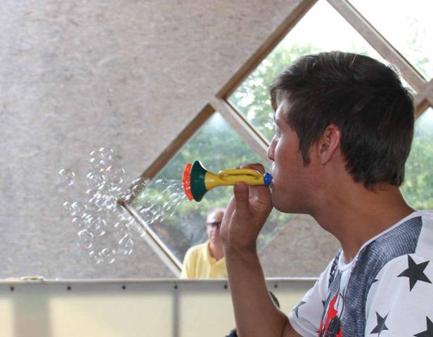 Ein Mann bläst mit einem Spielzeug Seifenblasen.