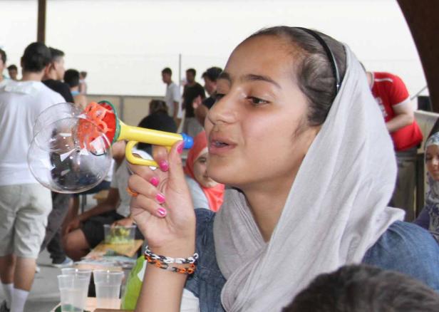 Ein junges Mädchen pustet mit einer Seifenblasenpistole Seifenblasen.