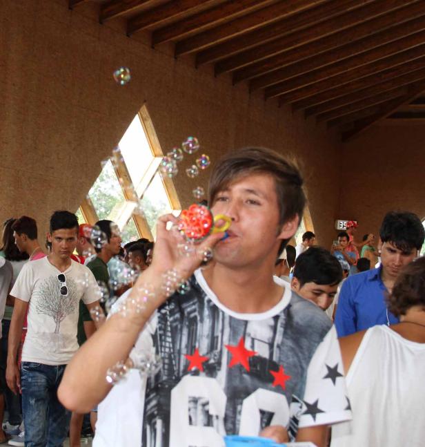 Ein junger Mann pustet Seifenblasen in einer Menschenmenge.