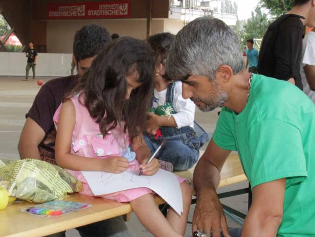 Ein Mädchen zeichnet mit einem Stift auf einem Blatt Papier, während ein Mann zusieht.