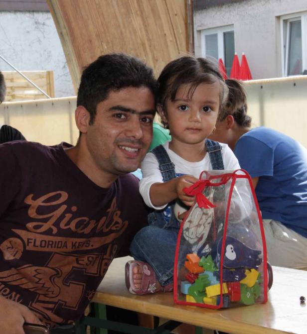 Ein Mann und ein kleines Mädchen sitzen an einem Tisch mit einem Spielzeugbeutel.